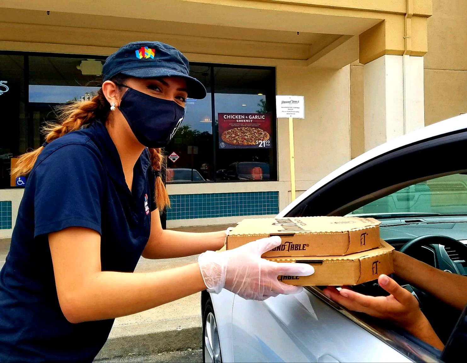 A young lady hand pizza to customers