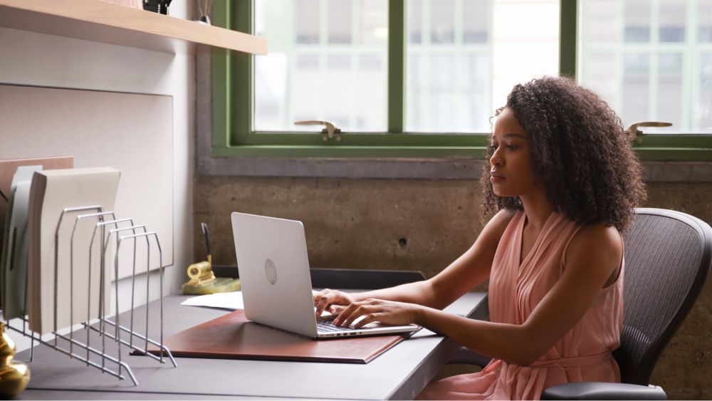 A black female staff work on a laptop