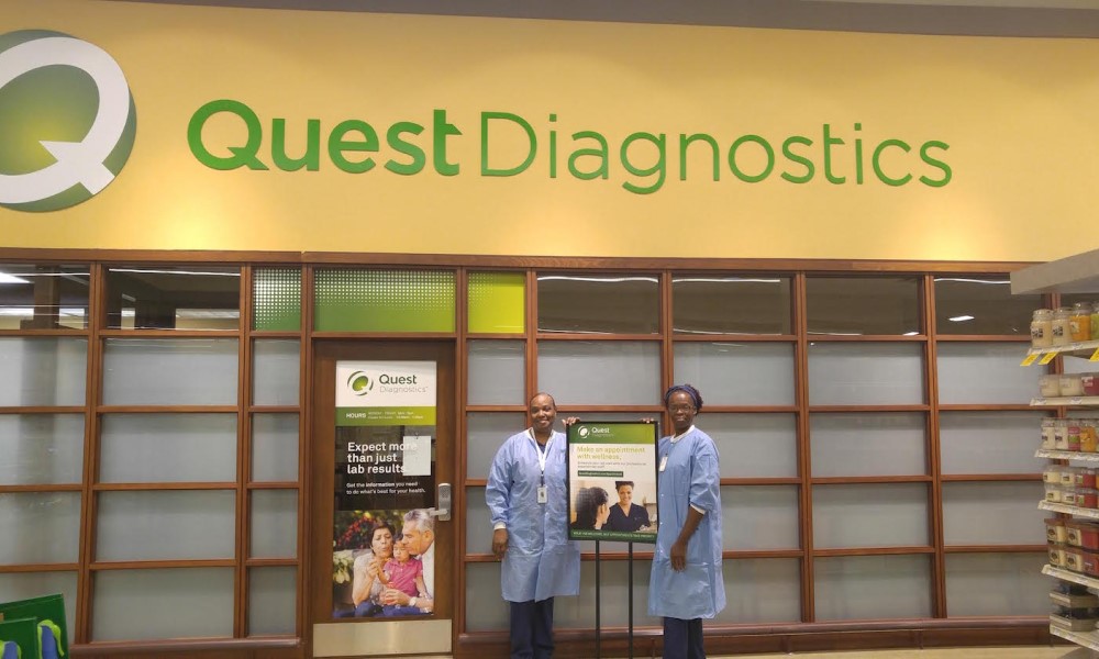 Quest Diagnostics staff stands in front of a banner
