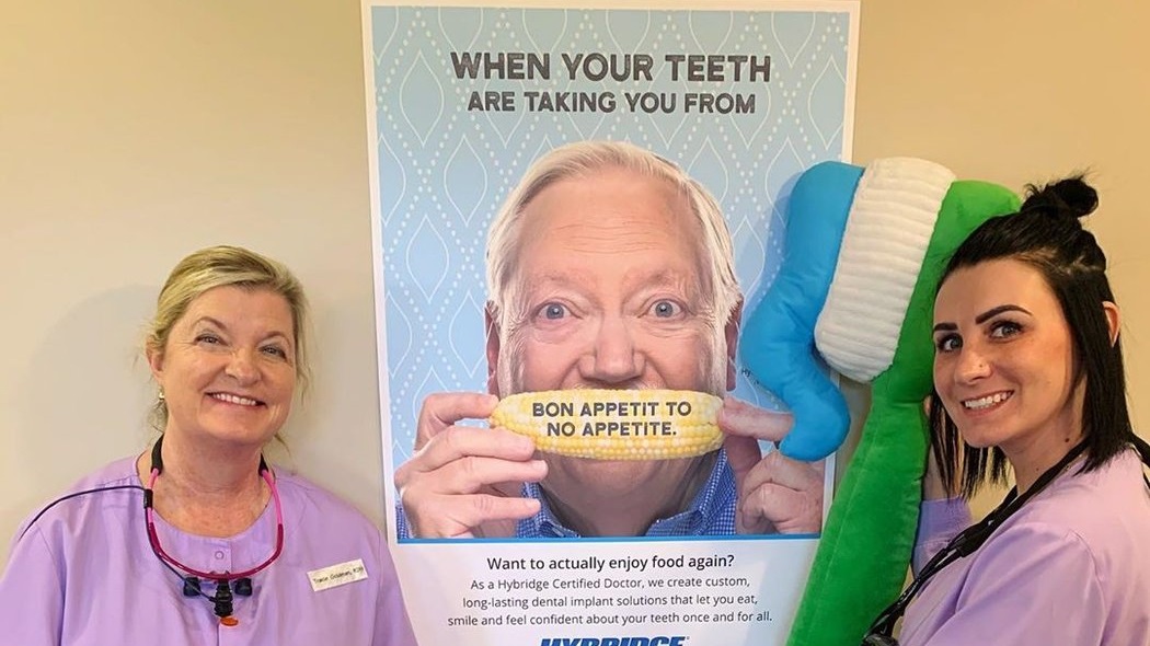 dental hygienist stands next to the banner