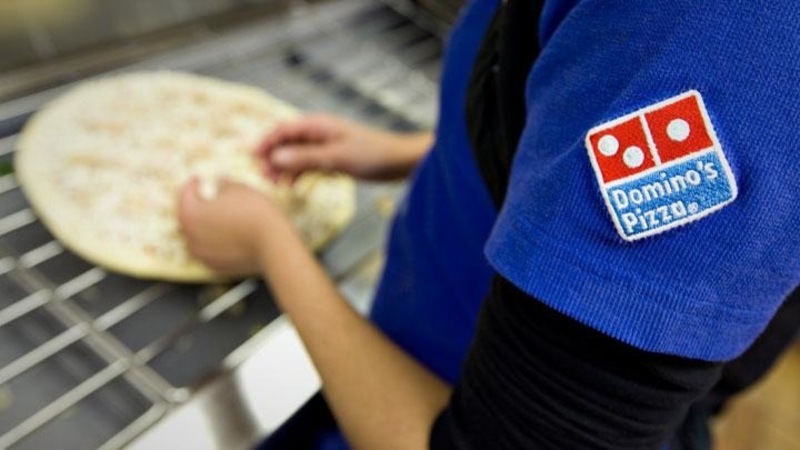 Staff prepares Dominos pizza for customers